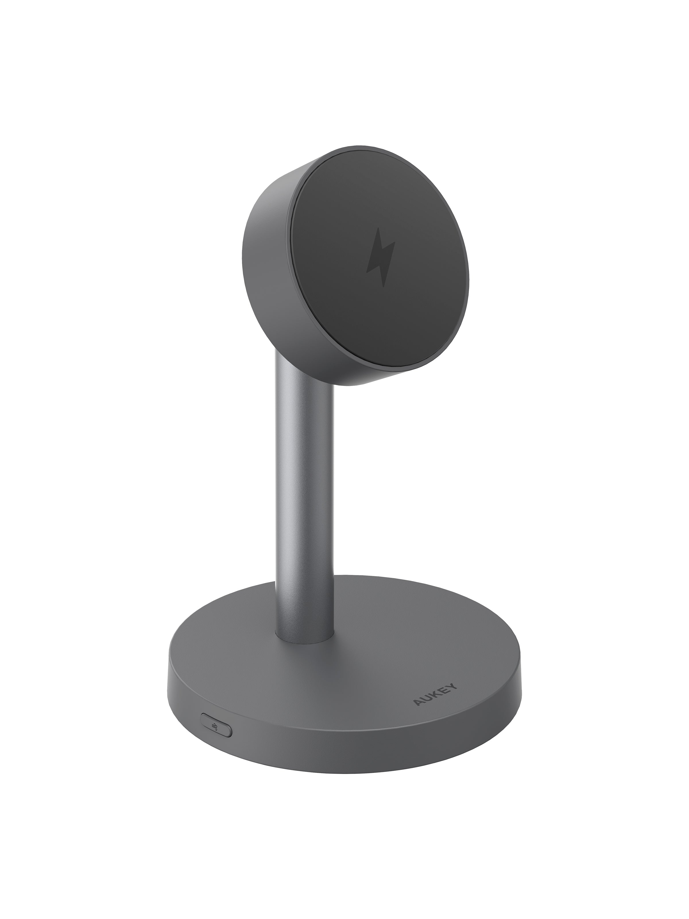 AUKEY LC-MC111 MagFusion magnetic wireless charging station with vacuum suction base holding smartphone upright on desk next to cup and book, demonstrating wireless charging and suction cup feature