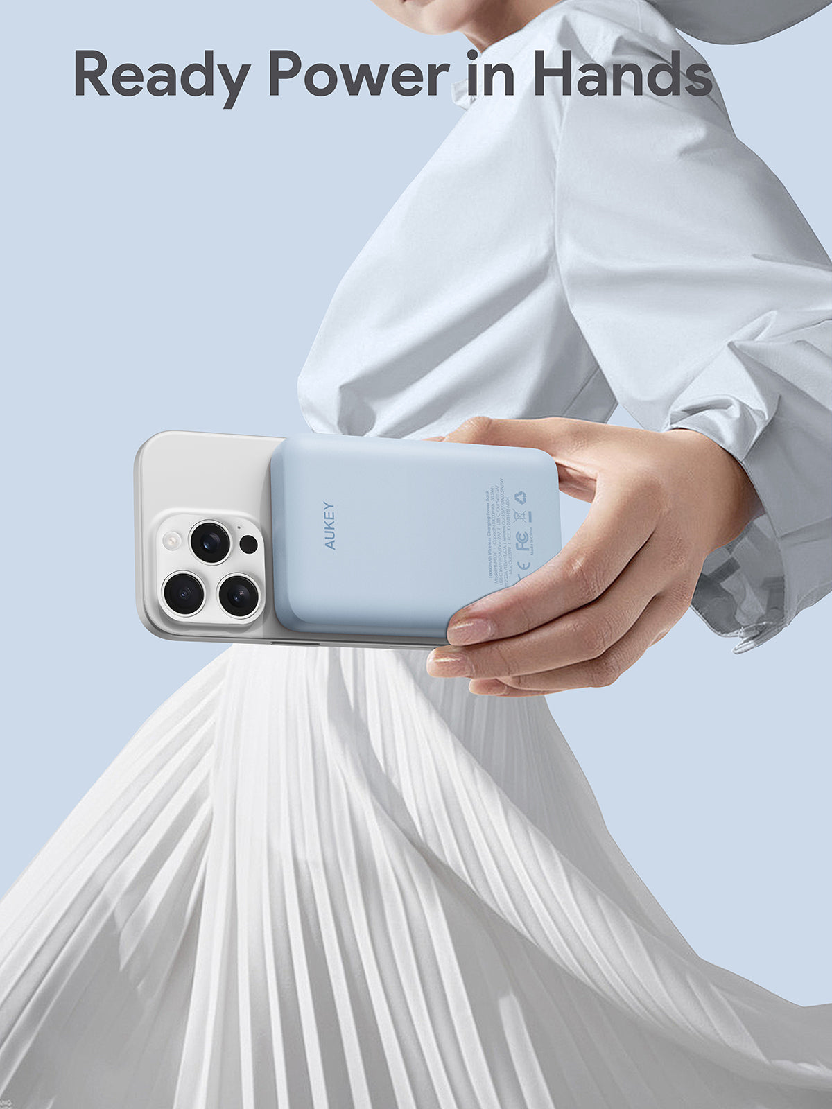 AUKEY MagFusion 10000mAh magnetic wireless charging power bank attached to smartphone in hand